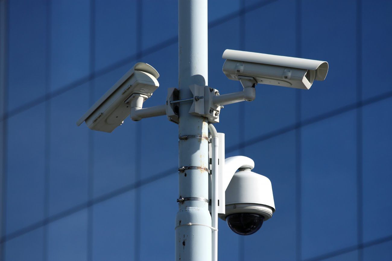 Câmaras de videovigilância num poste em frente a um edifício envidraçado