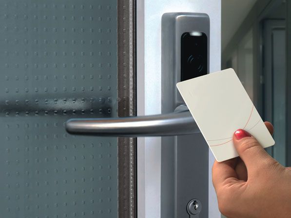 Mão a aproximar um cartão de um leitor de acessos numa porta